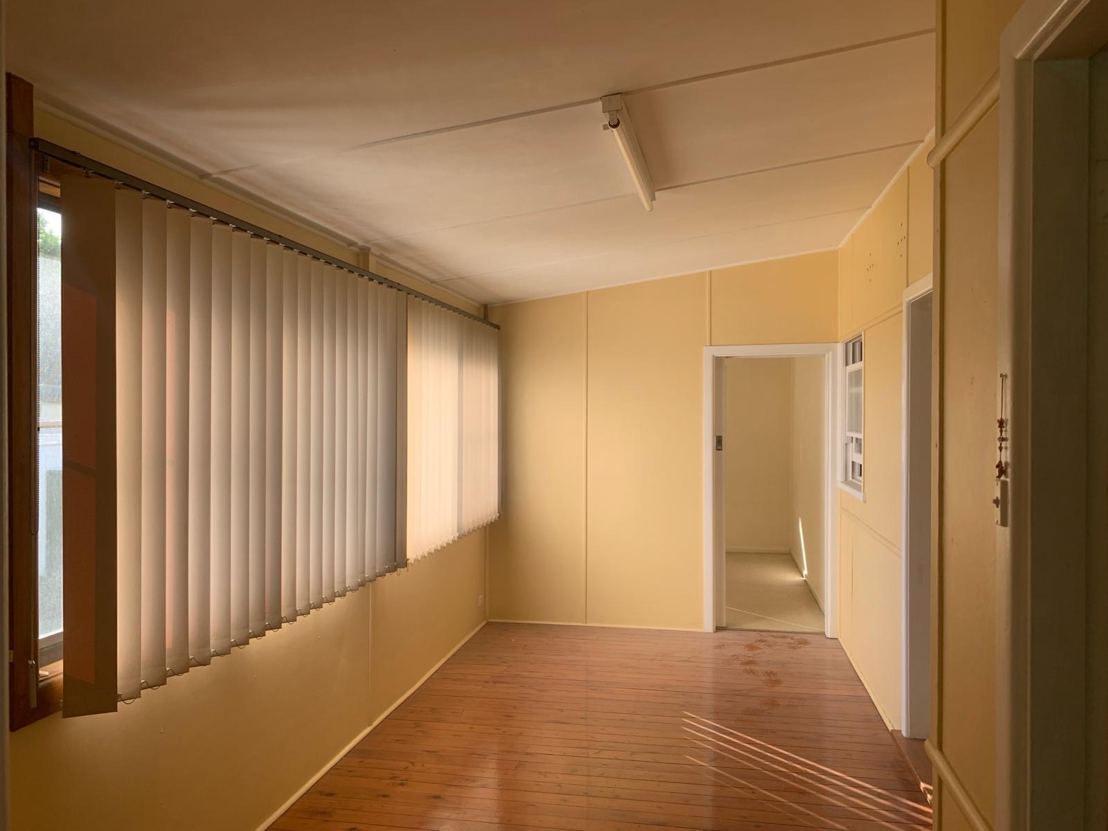 Sunroom before stripout — vertical blinds, lined walls and ceiling over hardwood floor