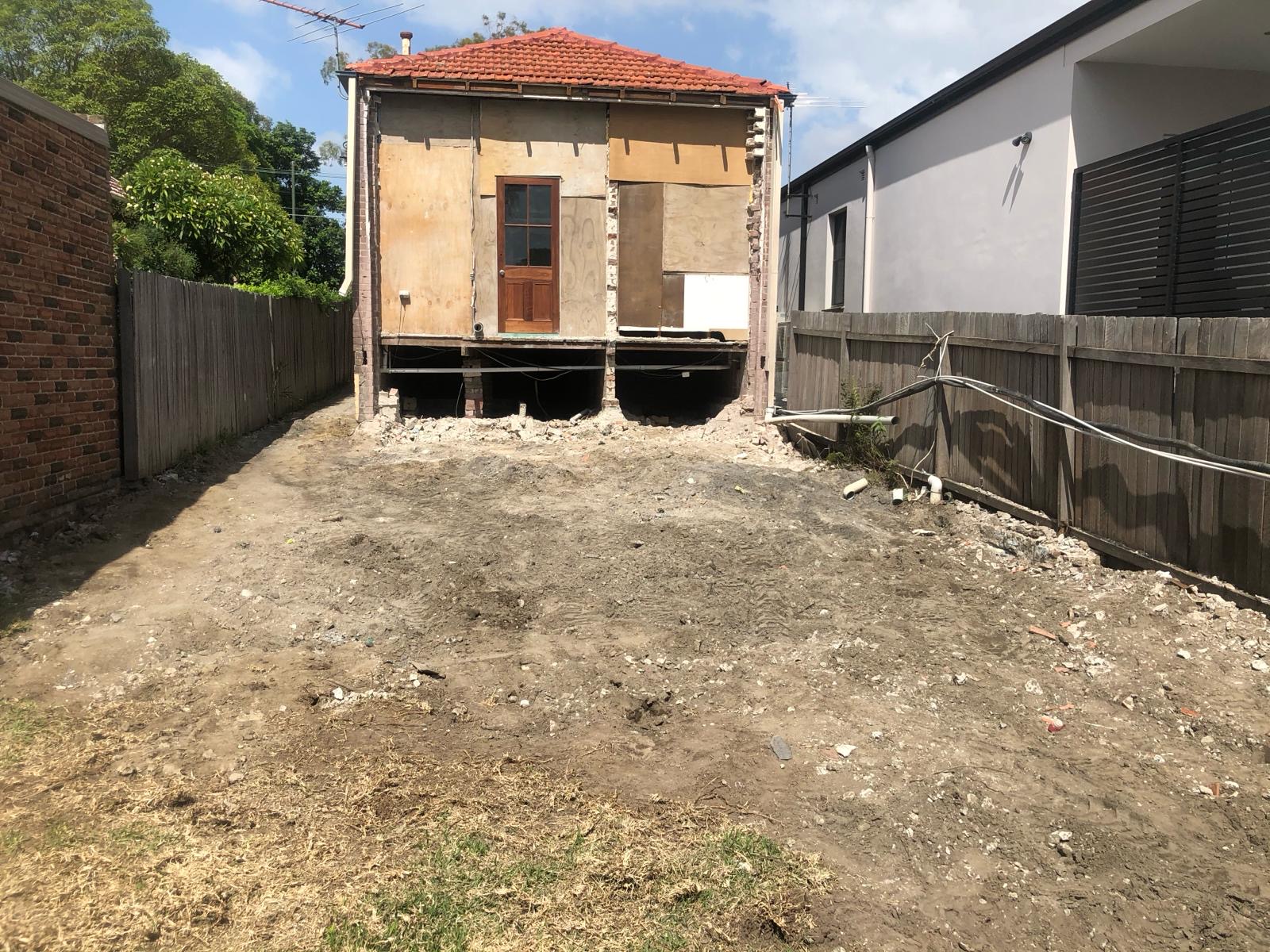 Same property after full rear strip-back — house stripped to the frame with backyard excavated and cleared