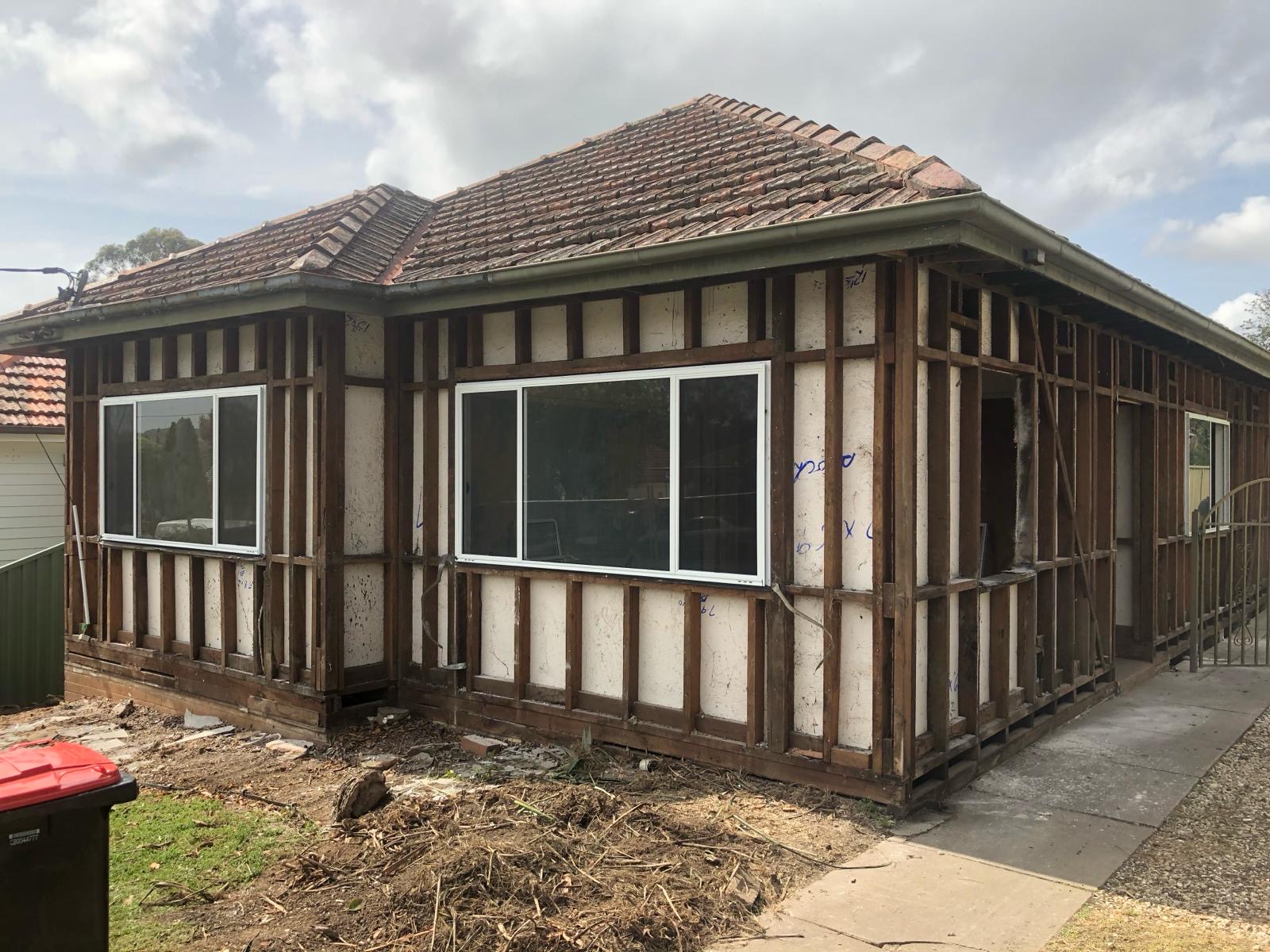 Same cottage after full strip-back — cladding removed down to exposed timber stud frame