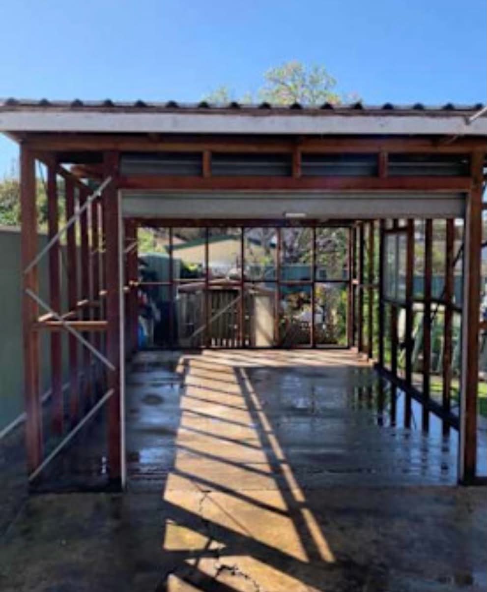 Backyard garage frame after asbestos-cement wall sheeting was safely removed and wrapped