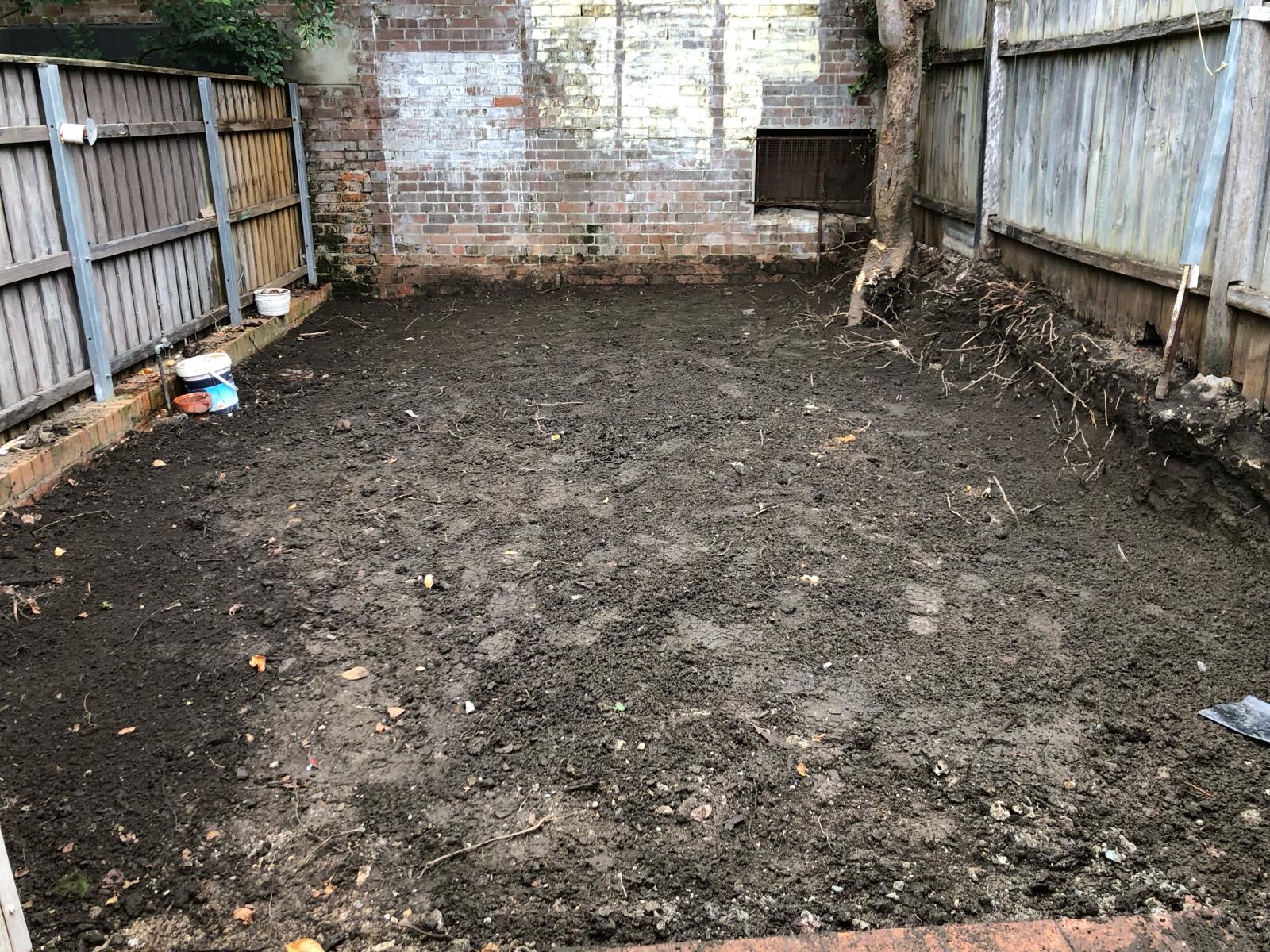 Courtyard after excavation — pavers and garden removed, soil levelled clean