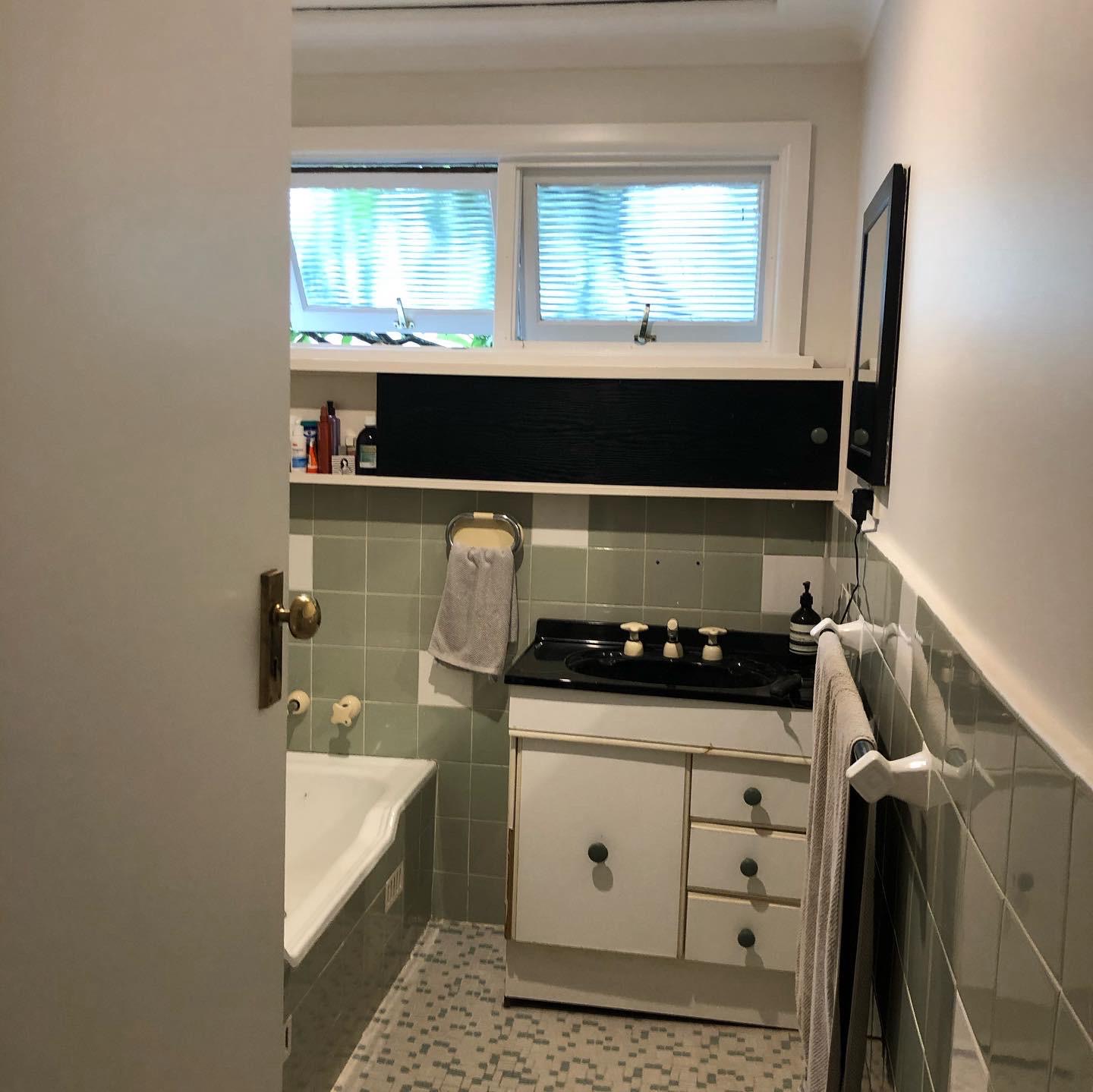 Bathroom before demolition — original green wall tiles, bath and vanity still in place