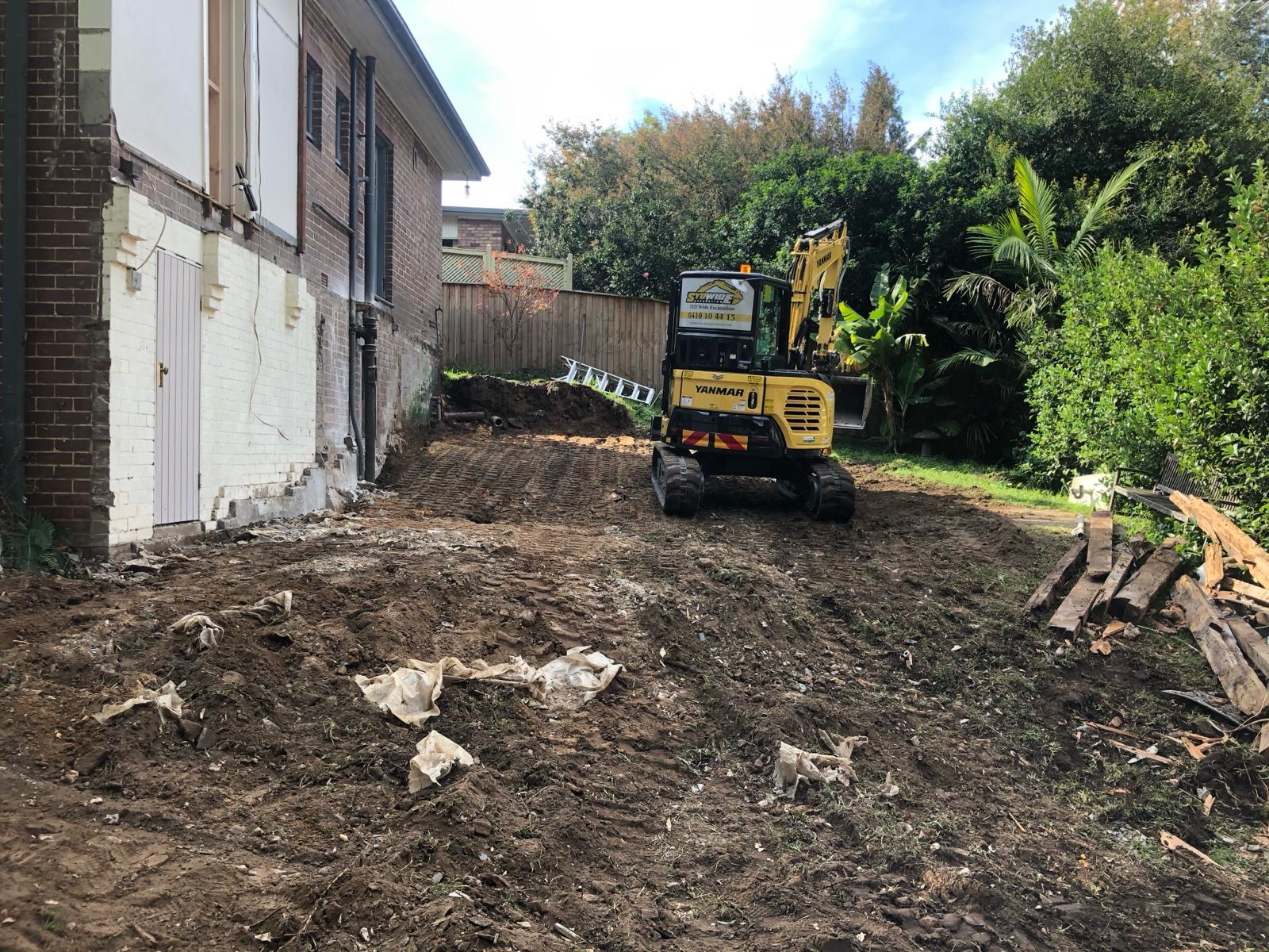 Same property after stripout — mini excavator clearing and levelling the backyard