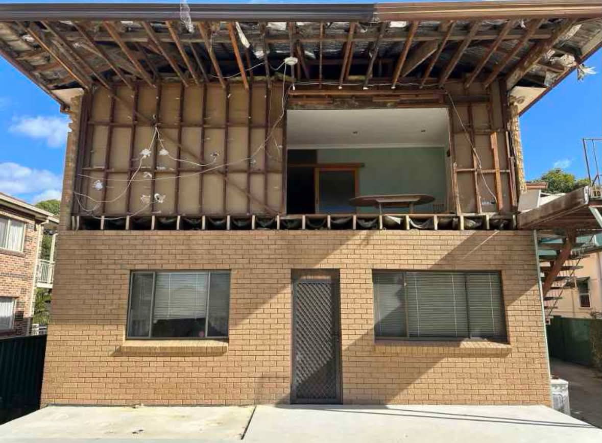 Same home after strip-out — upper level taken back to exposed timber wall and roof framing