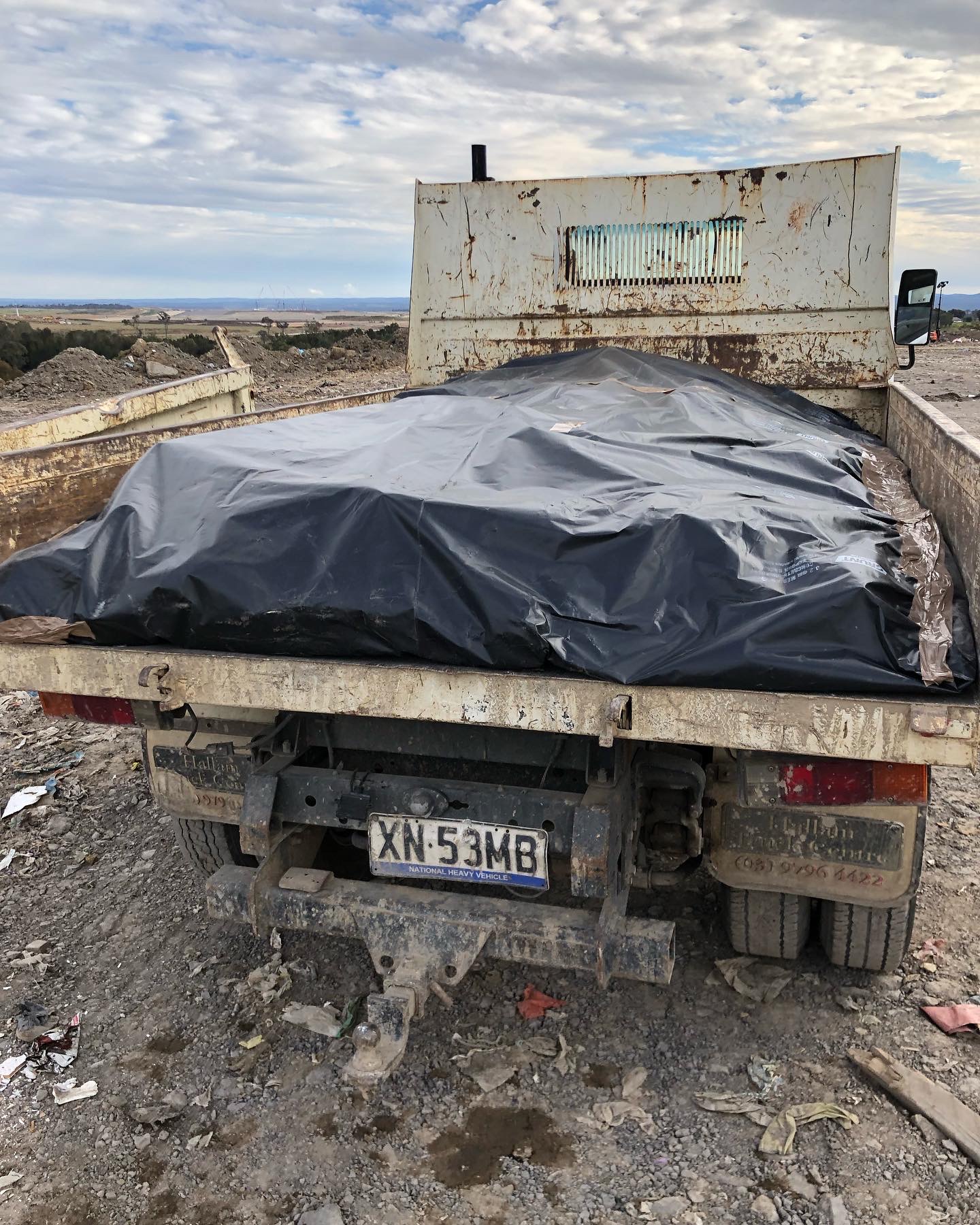Tipper truck loaded with asbestos sheeting fully encased in thick black plastic and taped, ready for the licensed asbestos tip at Kemps Creek